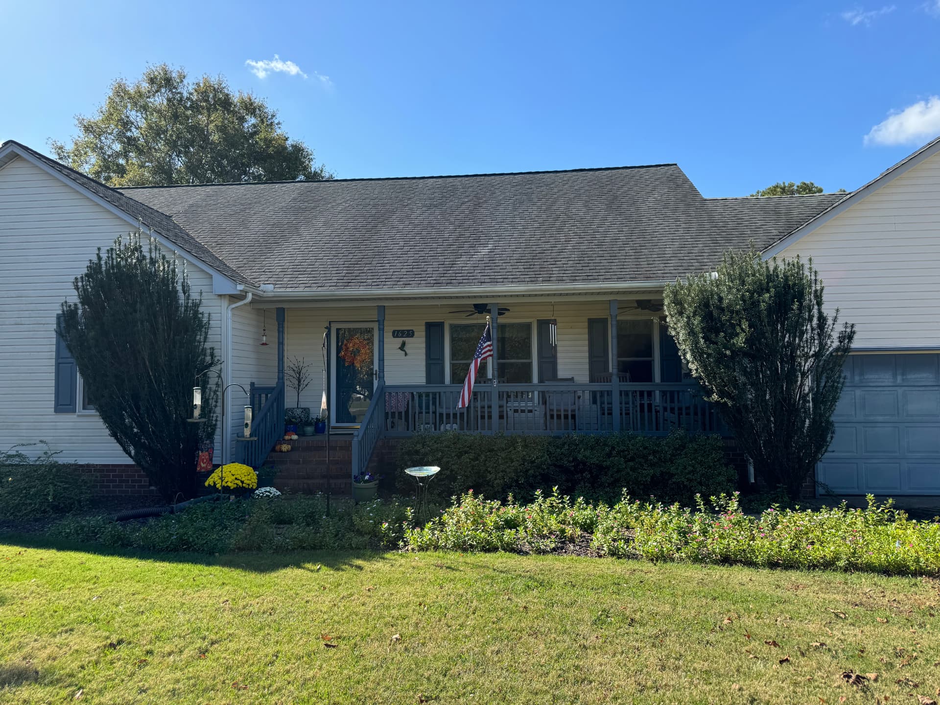 Front beds of a Pungo home with two large overgrown hedges flanking the porch before removal