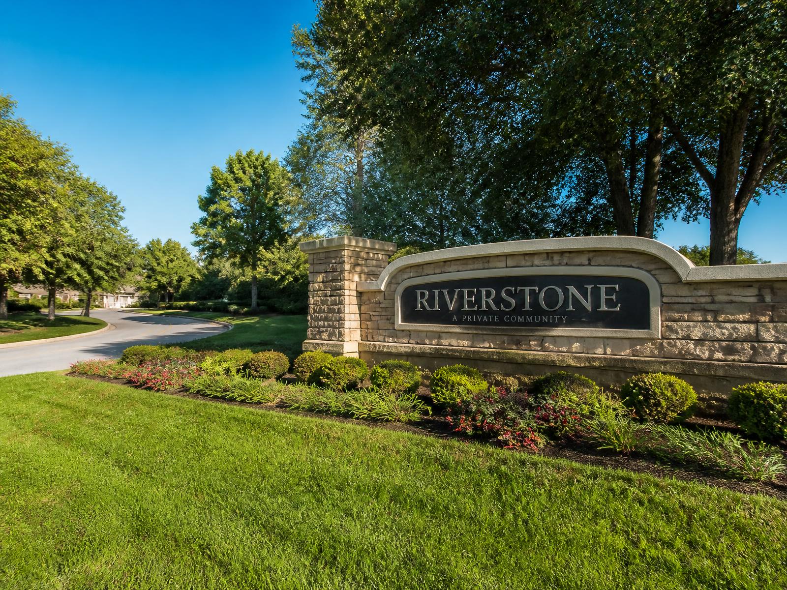 HOA community entrance with a monument sign, mown common area grass and trimmed shrub line